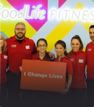 Six GoodLife Fitness associates holding a sign that says “I Change Lives”