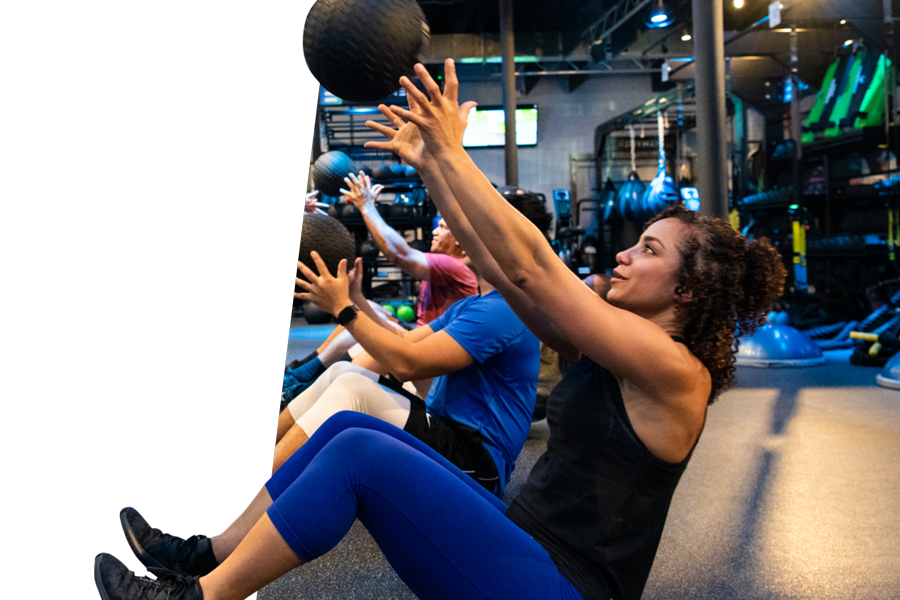 Woman sitting in boat position, catching a medicine ball.