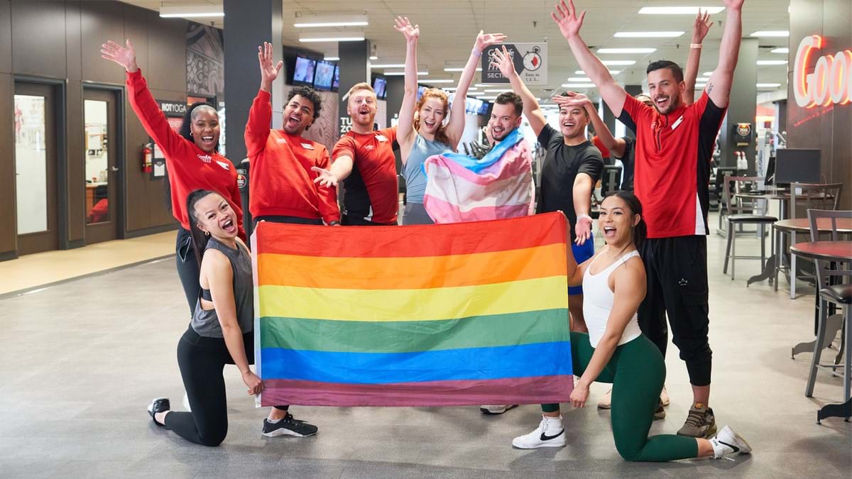 A group of associates holding a pride flag